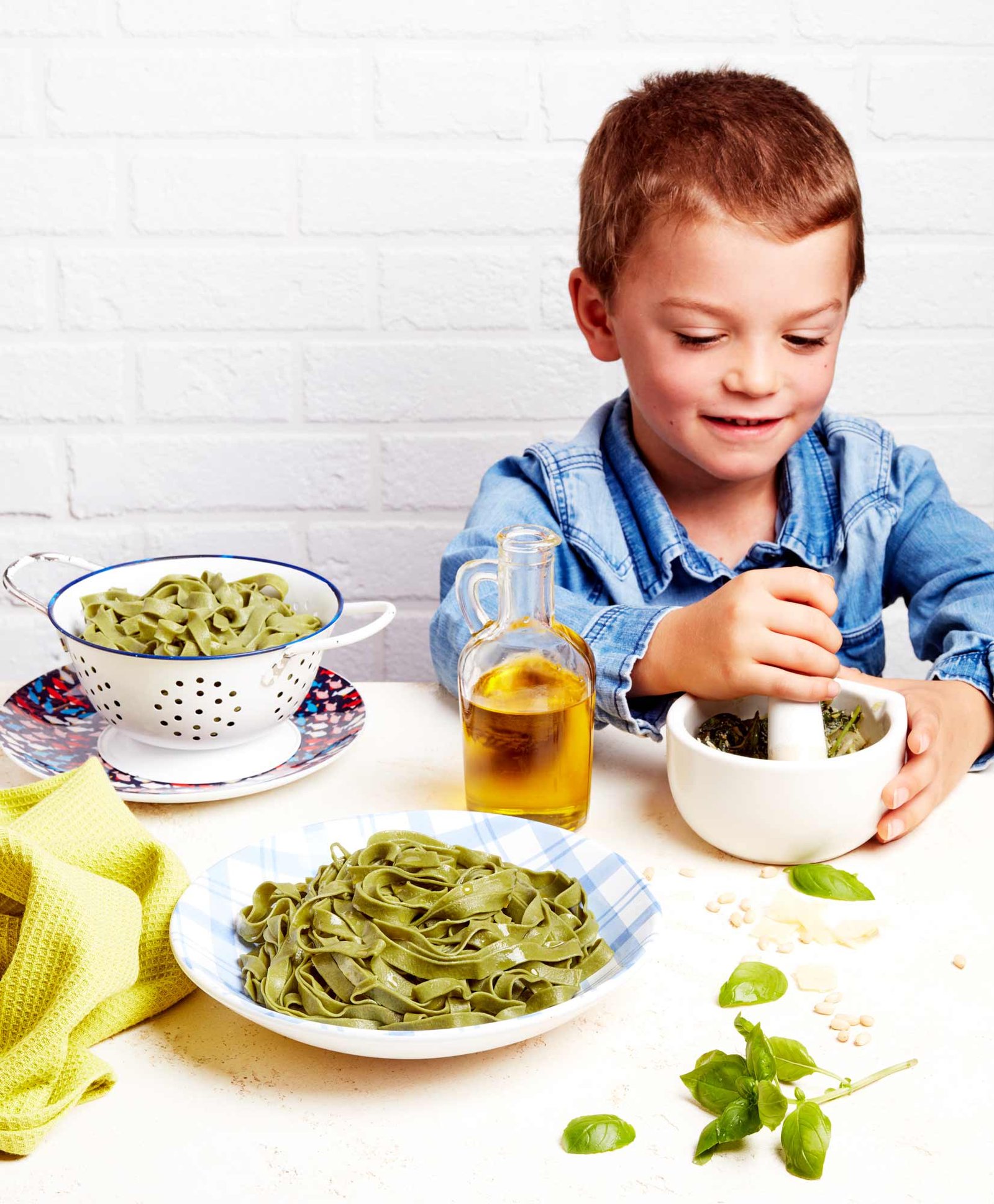 garçon pilant du pesto dans un mortier, assiette de tagliatelles à la chlorelle fait maison