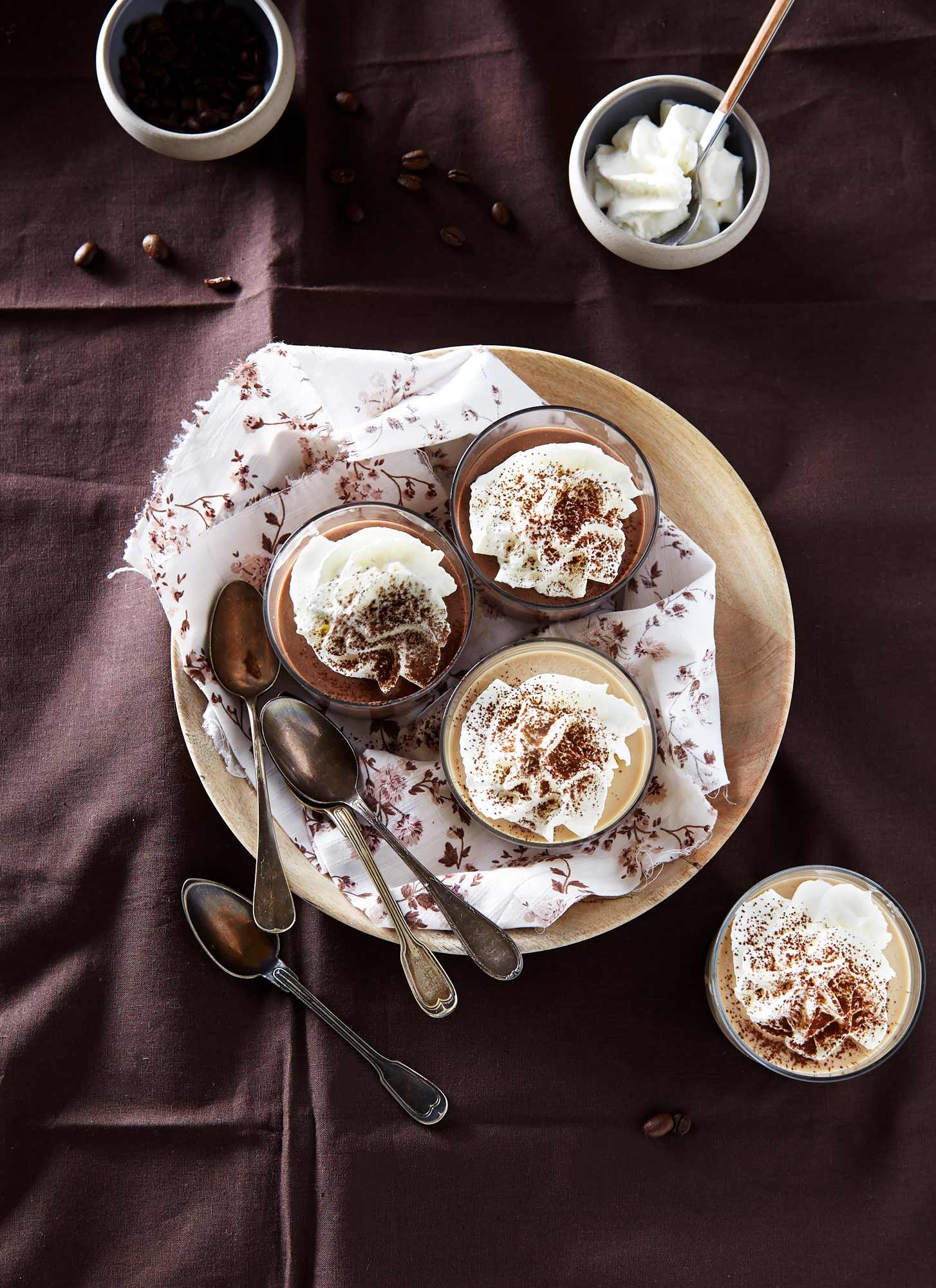 jolie photographie culinaire de petites crèmes au chocolat et au café avec chantilly saupoudrée de cacao sur tissu marron