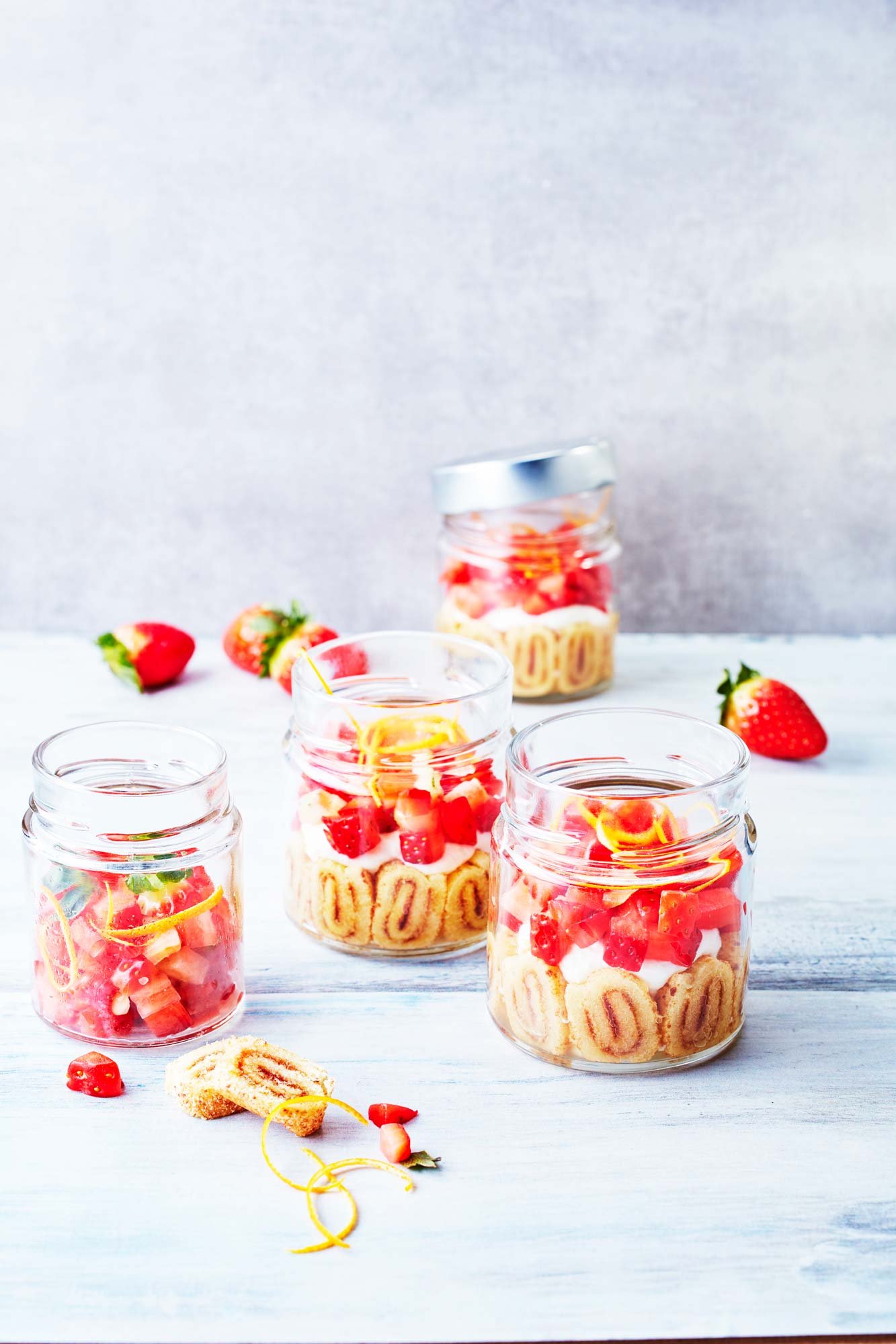 bocaux de charlottes aux fraises avec des fraises, des roulés à la fraise et de la crème
