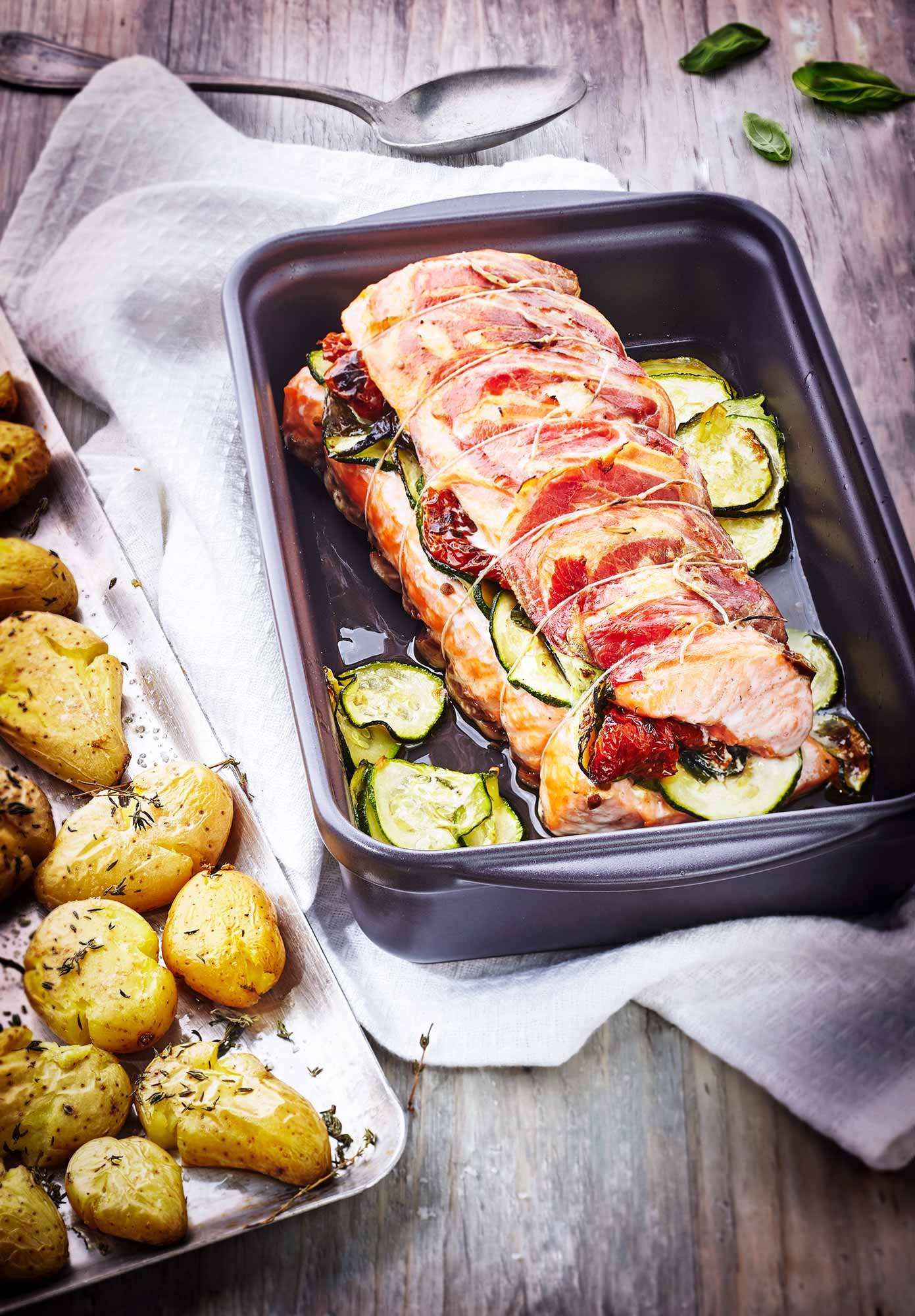 rôti de saumon aux courgettes et au bacon en plat à four, plaque de pommes de terre au four aux herbes