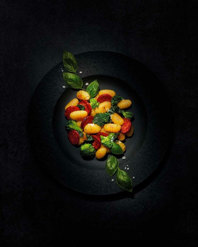 poêlée de gnocchis au chorizo et basilic élégamment disposés dans une assiette sombre
