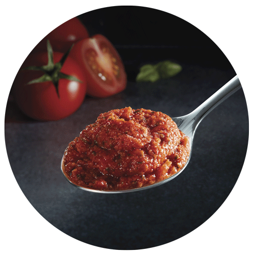 cuillère contenant du concentré de tomate avec tomates et basilic en arrière-plan pour le packaging