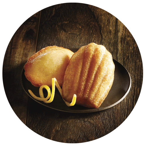 2 madeleines avec un zeste de citron dans une assiette sombre pris par un photographe culinaire packaging